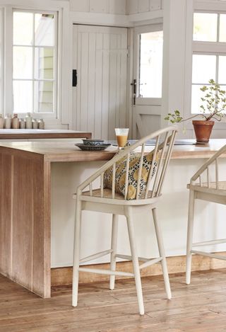 kitchen with wooden floor and high bar stool seat by wooden and white island