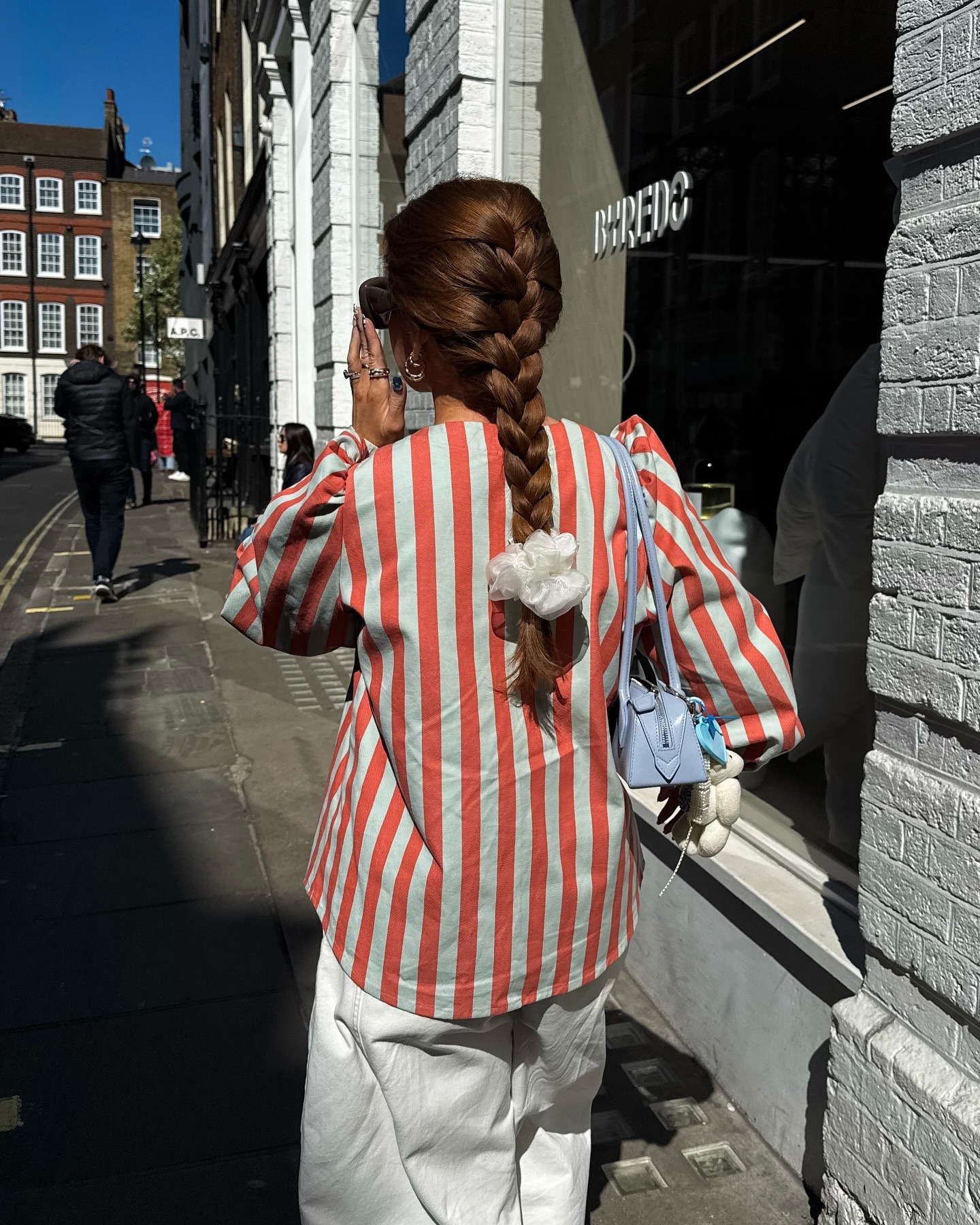 @rebeccaferrazwyatt wearing a striped blouse and a French braid secured with a large white scrunchie
