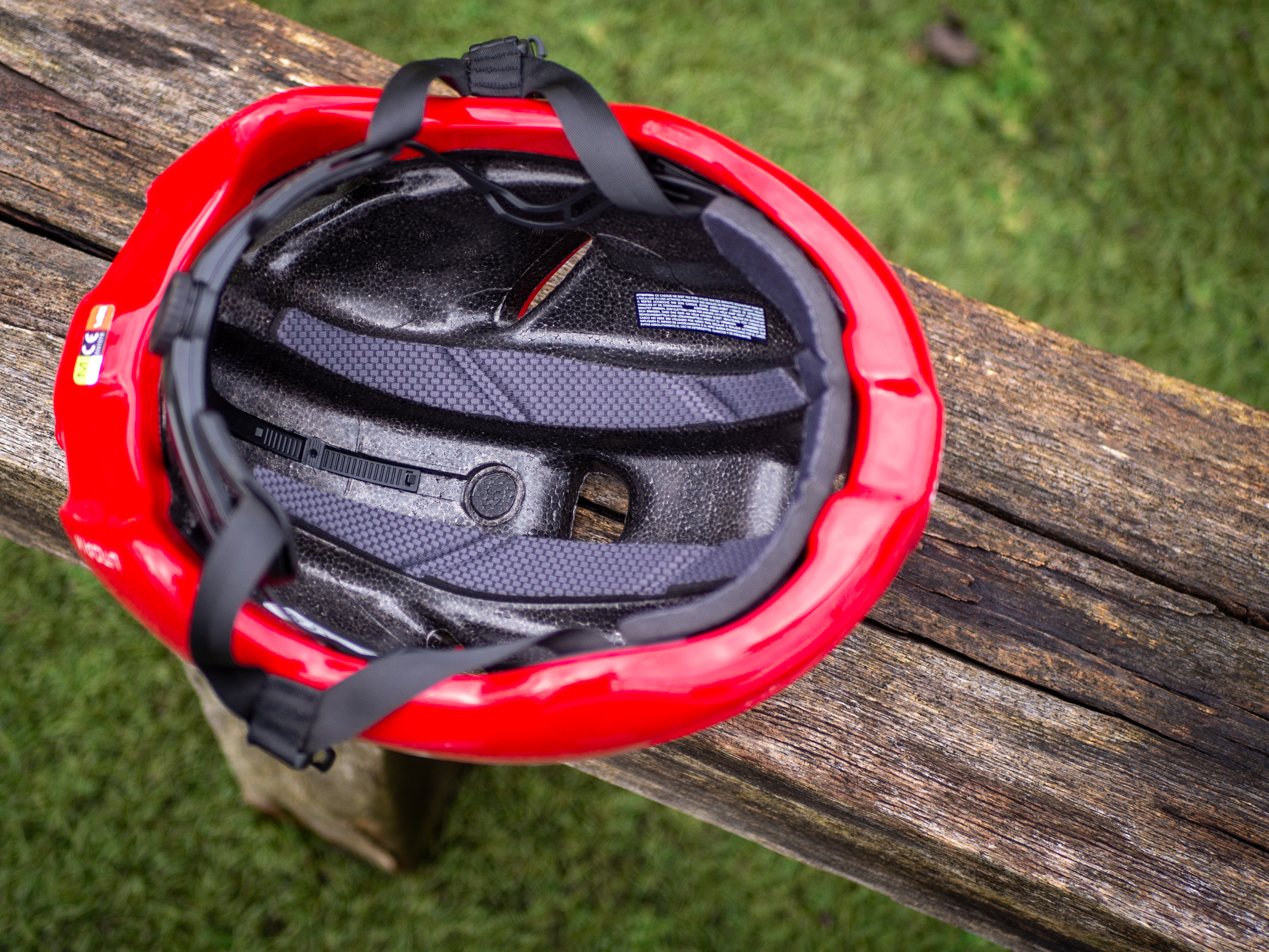 A red Kask Utopia Y aero helmet sits on a wooden bench