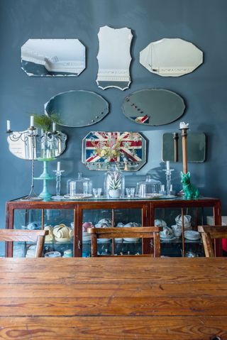 Arranged mirrors on a wall and over a glass and wooden antique cabinet