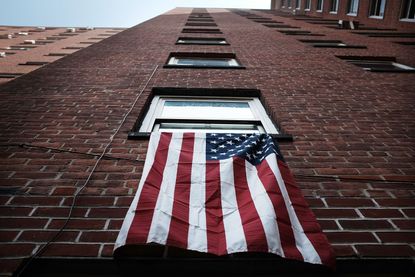 An American flag hangs from a window in an East Harlem public housing complex