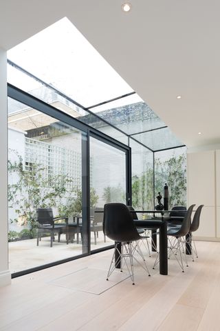 glass box extension with glass door and roof and plants outside