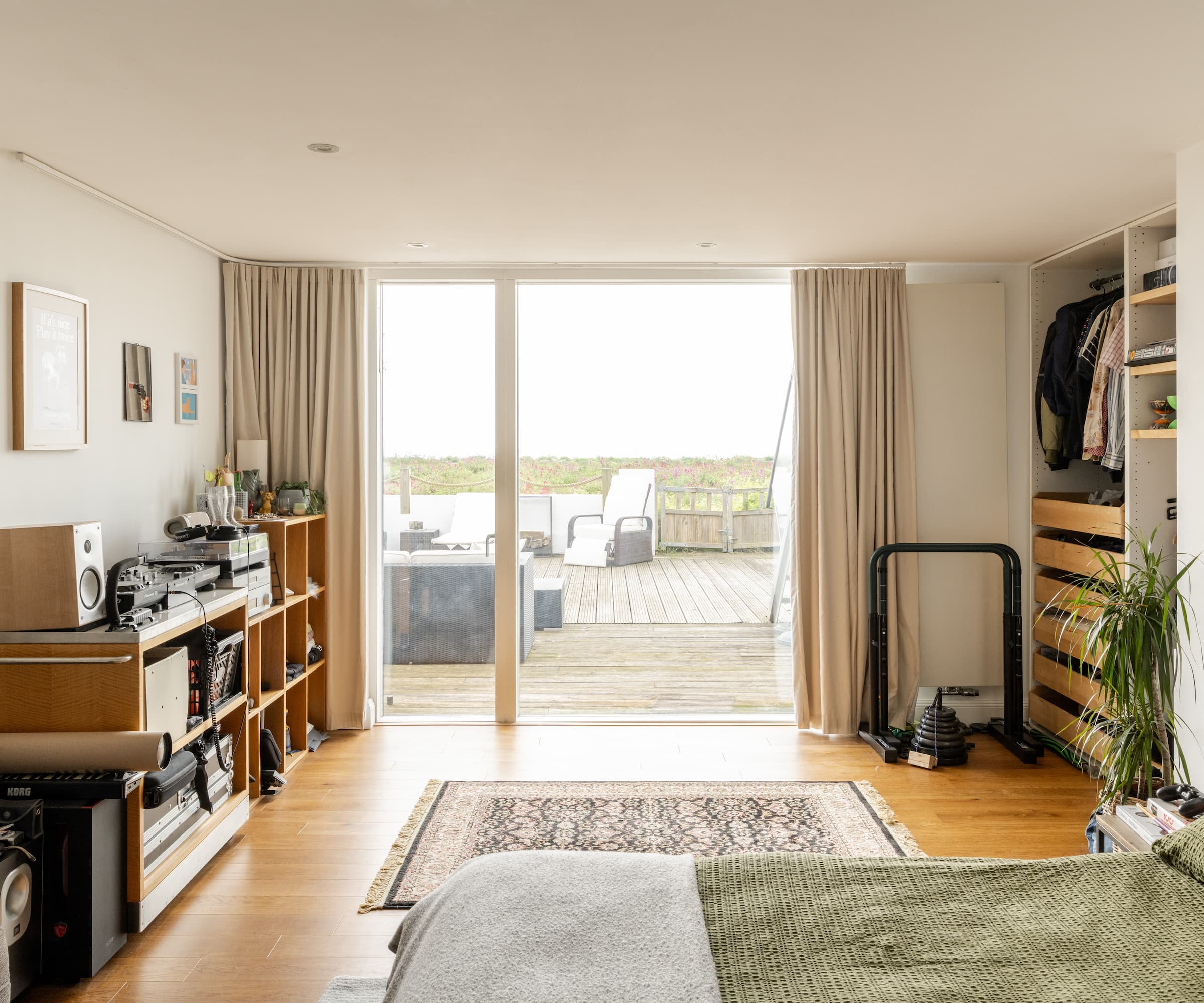 A bedroom with a bifold door looking out onto the sea and numerous shelving units