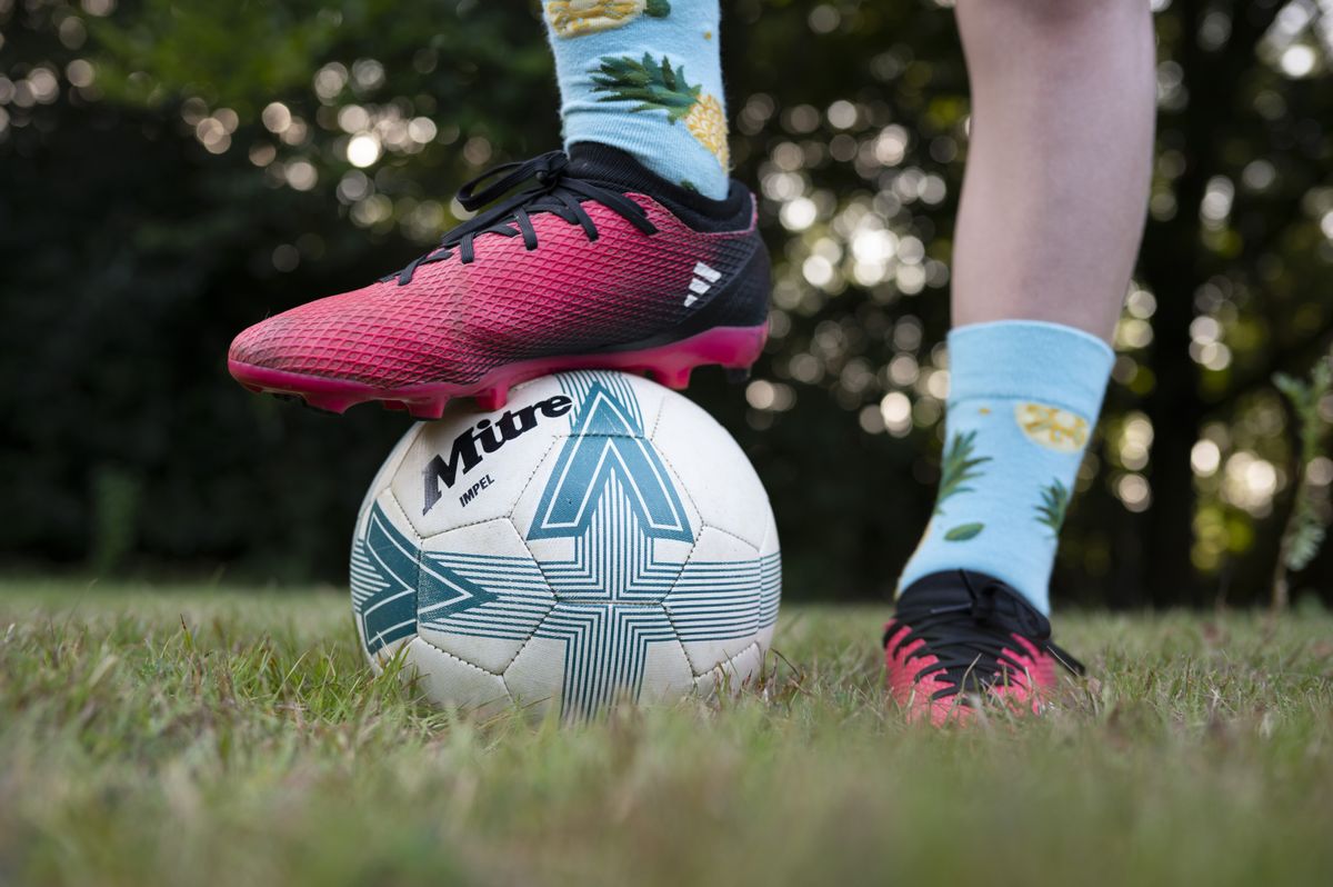 Closeup of a footballer's feet, with one foot standing on top of a ball
