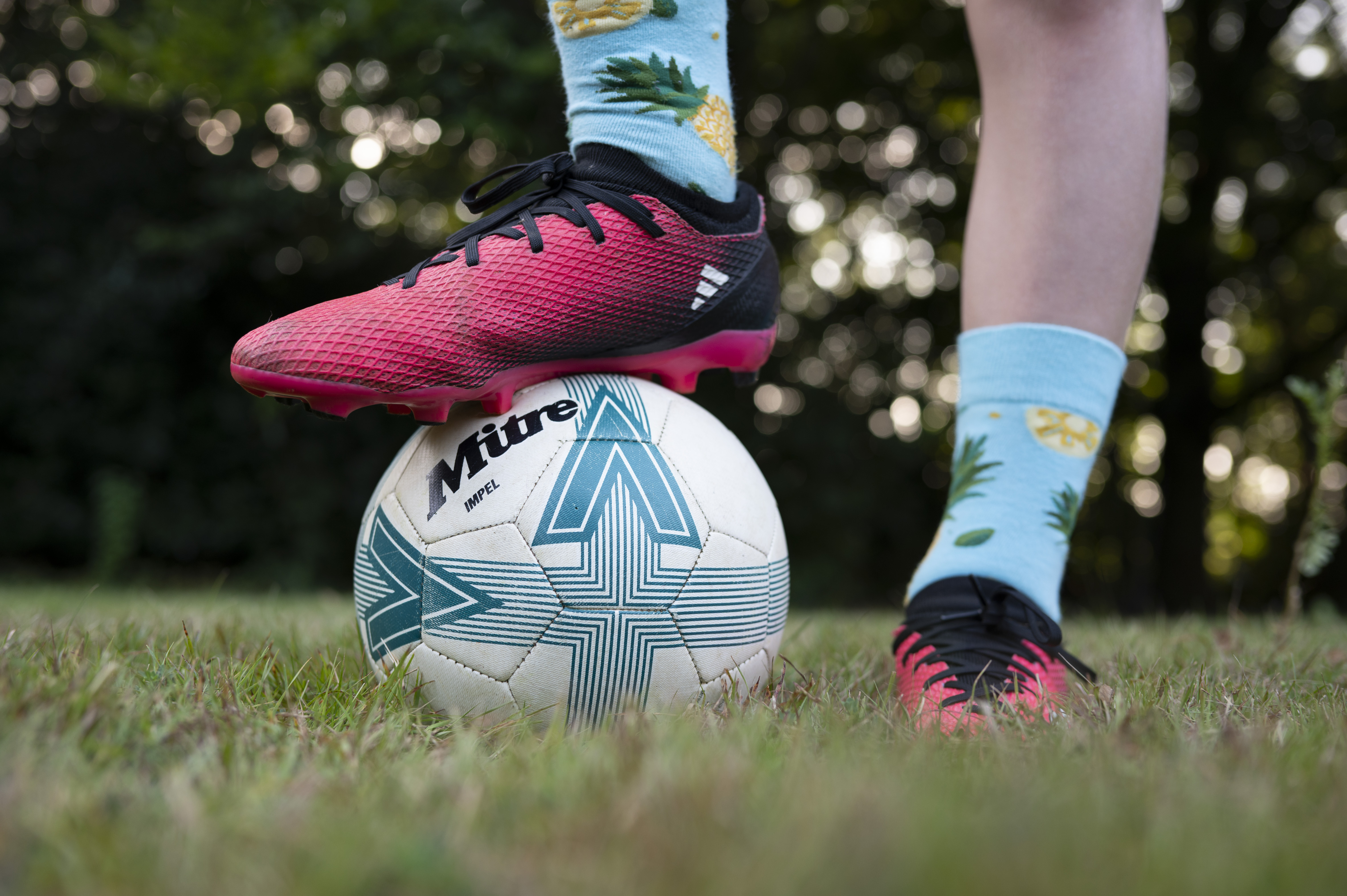 Closeup of a footballer's feet, with one foot standing on top of a ball