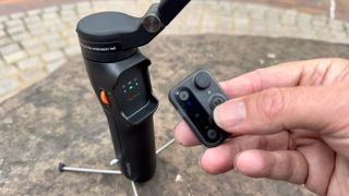 Hohem iSteady V3 gimbal and remote control held in a hand