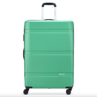 a green delsey paris suitcase in front of a plain backdrop