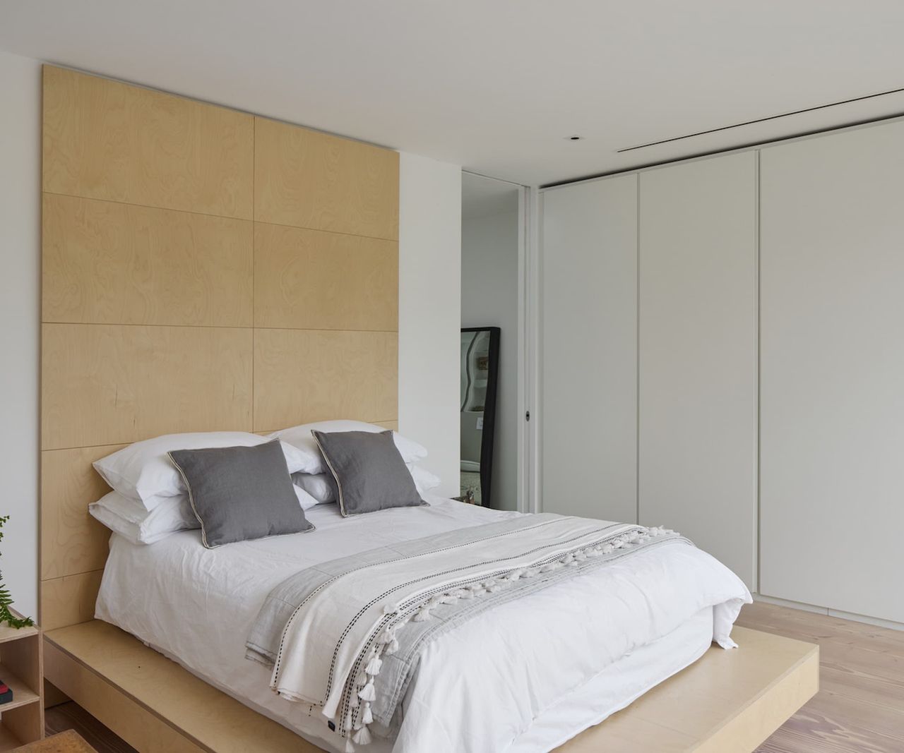 A bed on a raised platform with a wooden backboard