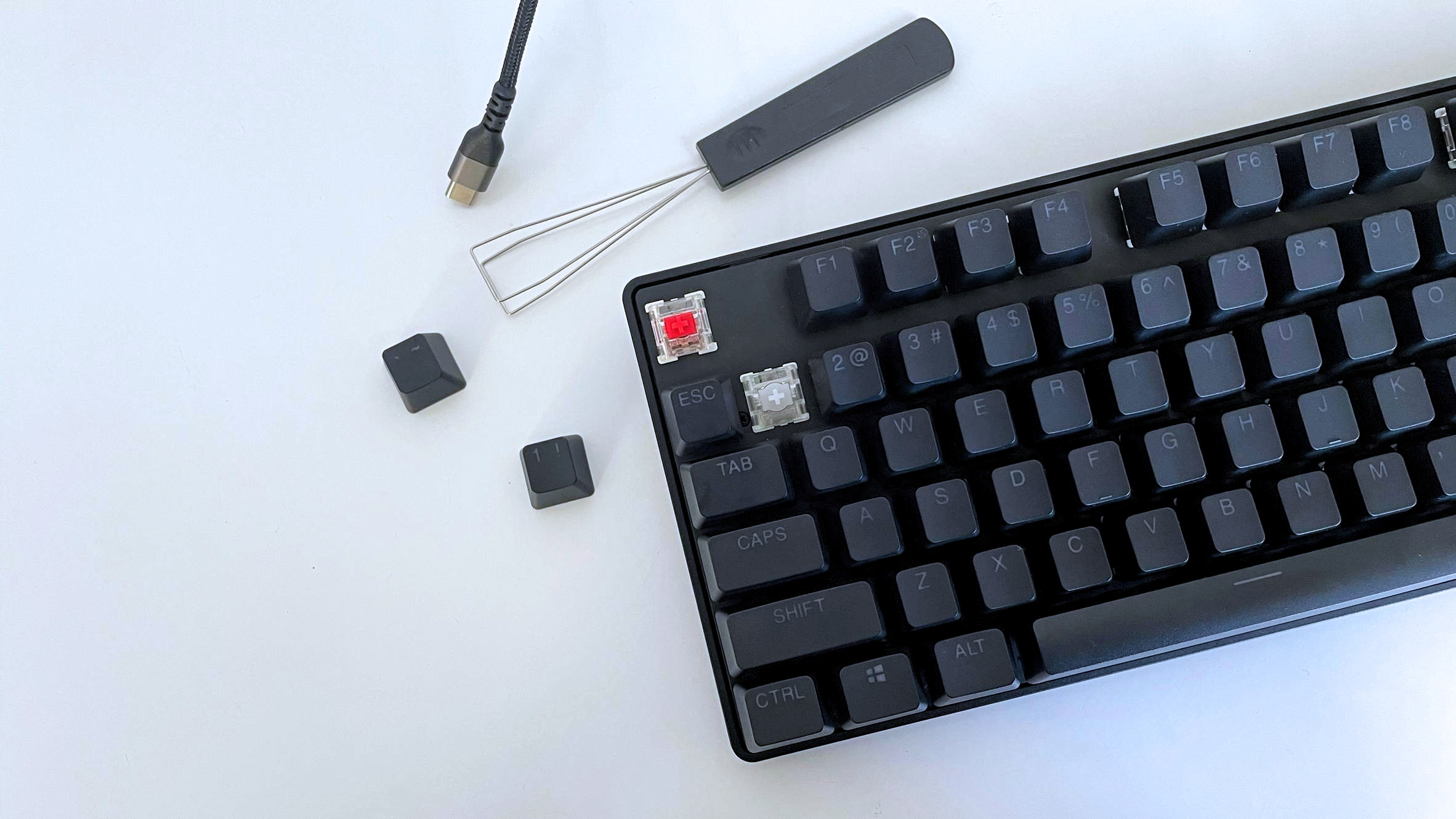 The SteelSeries Apex Pro Gen 3 TKL with two keycaps removed next to a keycap puller