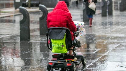 A wheelchair user on a rainy pavement