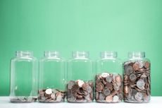 5 glass jars containing various US coins in ascending order of fullness, green background