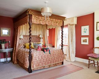 red bedroom in country home with four poster bed