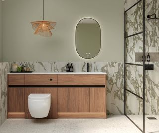 bathroom with green painted walls and green and white fluted tiles, wooden vanity units with back to wall toilet, rattan pendant light and bathroom mirror with integrated lighting