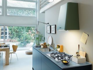 modern open plan kitchen diner with a green cooker hood and blue handleless cabinets