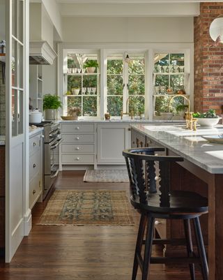 a kitchen with rugs, brickwork and shelving in a window