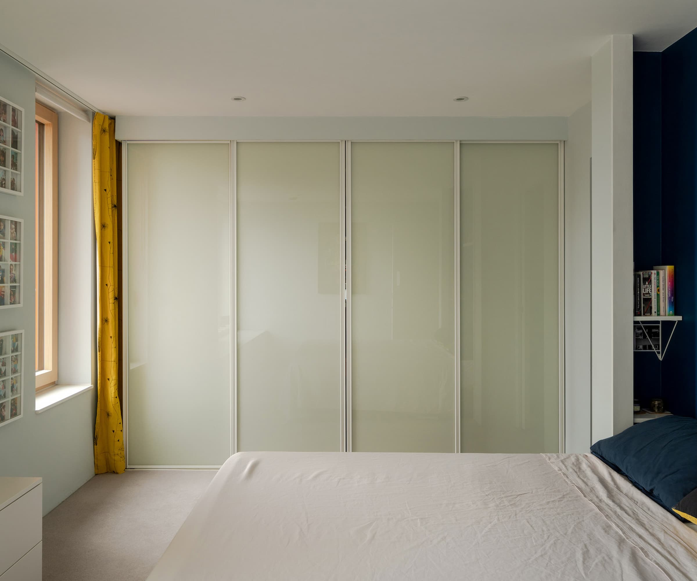 A bedroom with inbuilt wardrobes and a black back wall