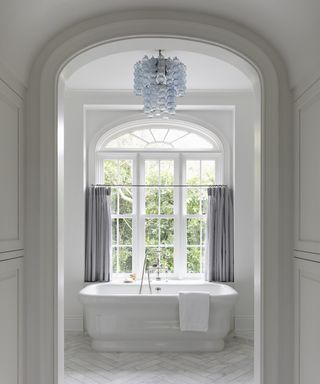 Bathroom curtain ideas with a grey half curtain over an arched window, with bath next to it