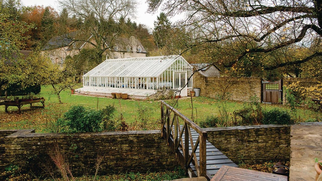 Exterior view of a large greenhouse in a vegetable garden.