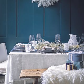 Christmas dining room tablescape, with white and green accessories lining the middle of the table