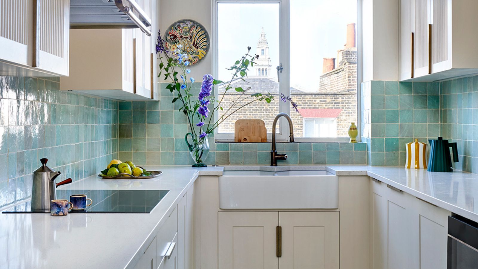 Bright galley kitchen with white cabinets, pale green tiled splashback and matching tiled floor.