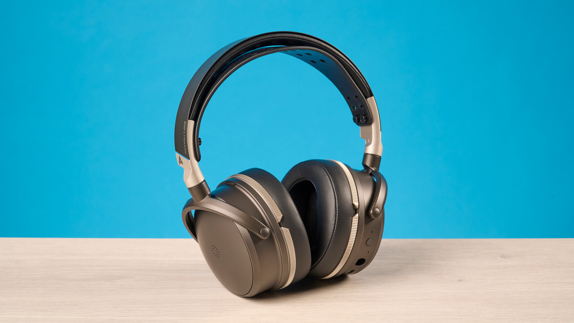 The Audeze Maxwell 2 ANC on a wooden desk with a blue background