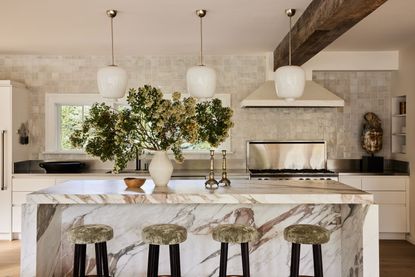 a kitchen with a marble island and zellige tile walls
