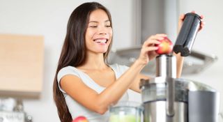 A woman juicing an apple in a juicer