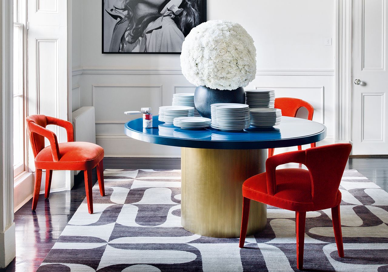 white dining room with gold table and red chairs