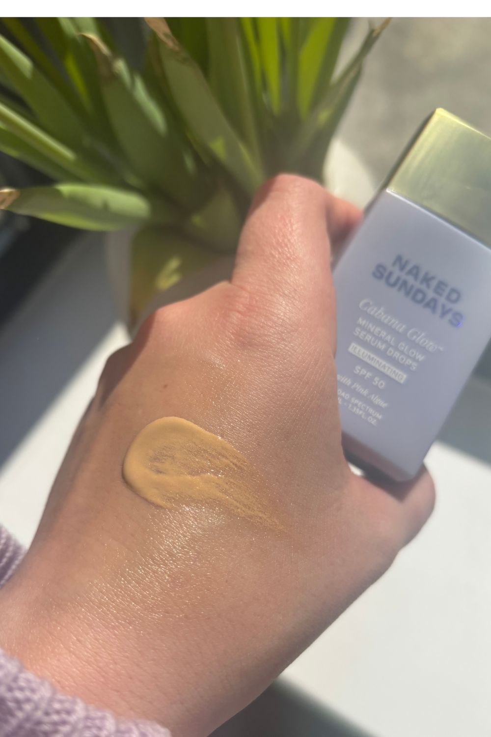 a hand with a smear of the naked sundays cabanaglow mineral glow spf serum drops