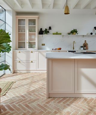 pink modern kitchen with a herringbone terracotta tiled floor and marble countertops with backsplash