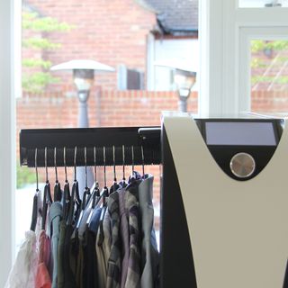 A close up of the Effie ironing machine with clothes hanging from it