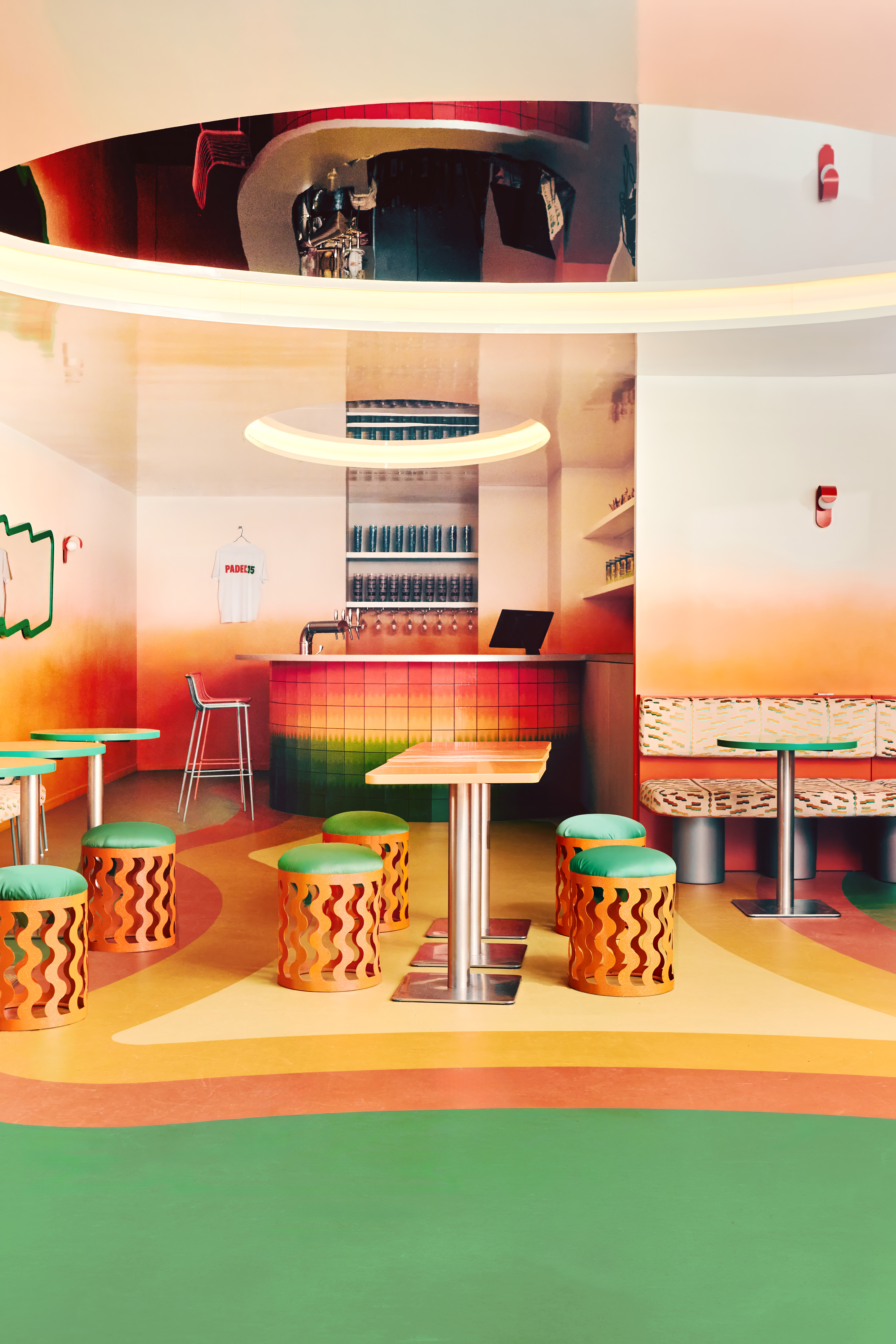 The restaurant and bar of a sports club features gradient green, orange, ochre, and yellow floors, walls, bar tiles, and furniture, each characterized by a whimsical essence.