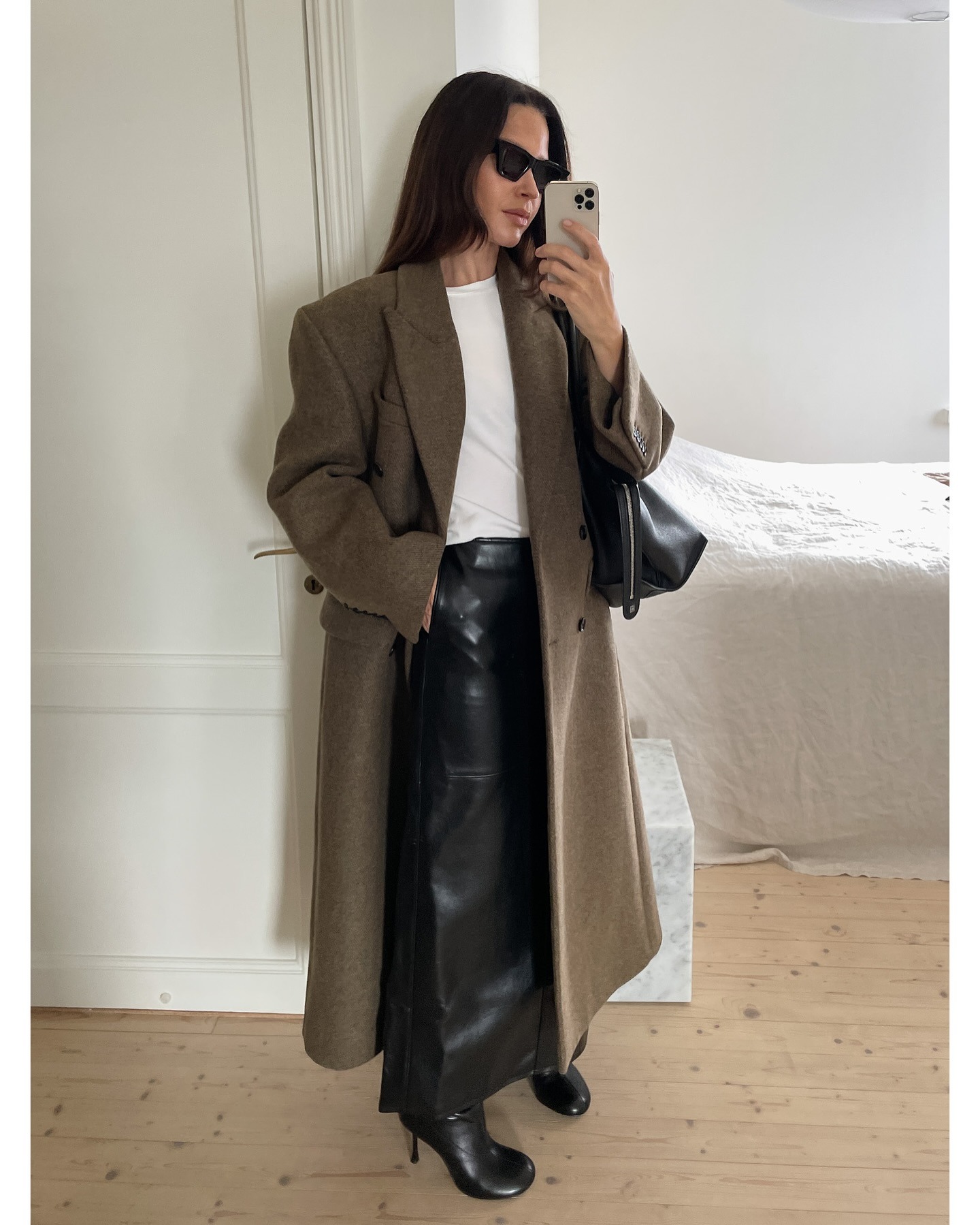 Johanna Piispa wears a long black leather skirt, black leather boots, a double-breasted tweed blazer, a white tee, a black tote, and sunglasses.