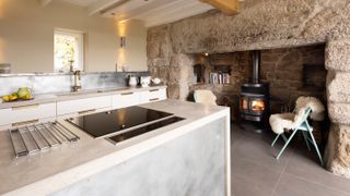 large stone inglenook fireplace with new woodburning stove in kitchen