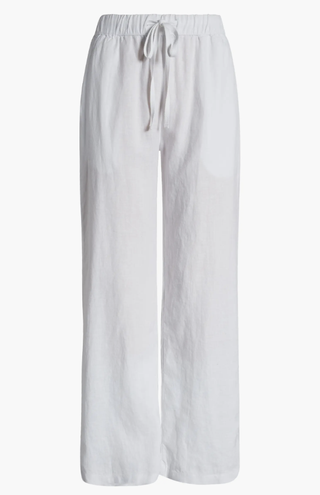 a pair of white linen pants by calson in front of a plain backdrop