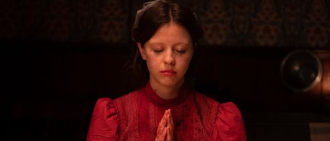 Mia Goth prays at the dinner table, with bloodied hands, in Pearl.