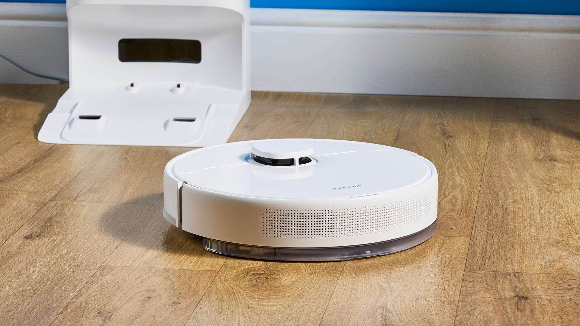 Dreame D10 Plus Gen 2 photographed on a wooden floor in front of a blue backdrop