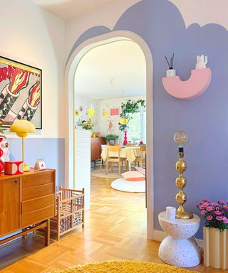 A lavender small entryway with colorful decor, onlooking a living room