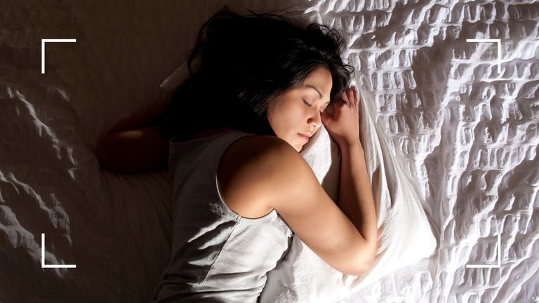 Woman sleeping in white bedsheets with sun coming through the window after learning how to sleep in the heat