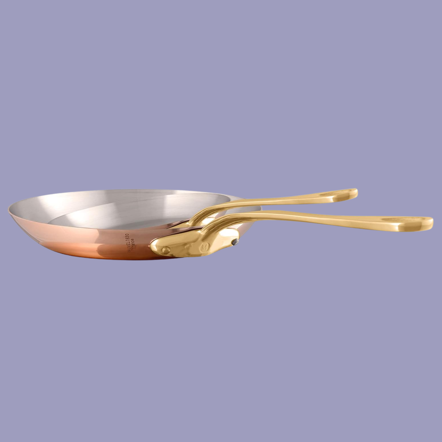 A set of two polished copper and stainless steel frying pans by Mauviel, against a lilac purple background
