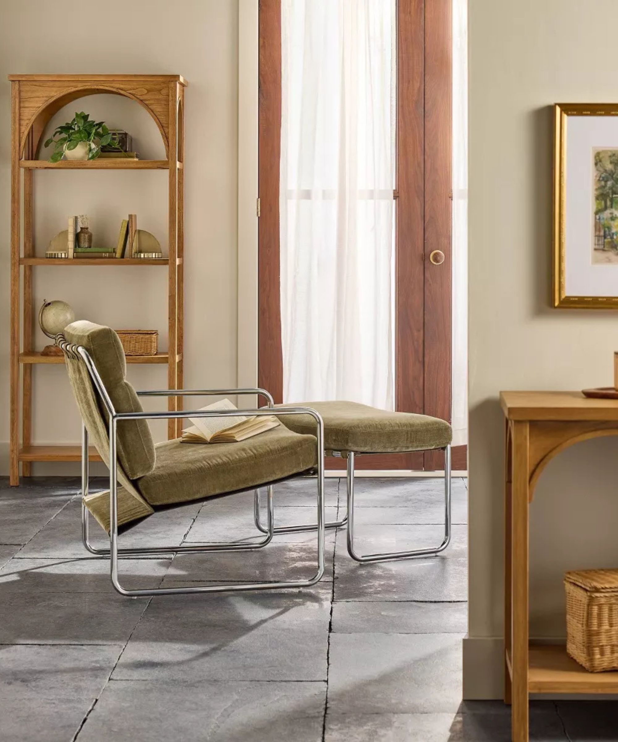 An entryway with stone floors and a curved bookcase on the far wall with a green velvet and chrome mid-century modern style chair and ottoman