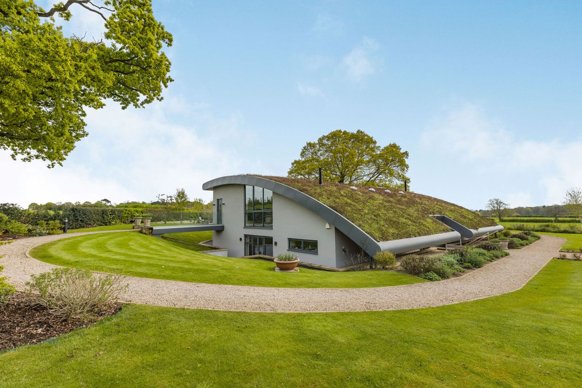 Outside view of a hobbit house built into a hill with a grass roof