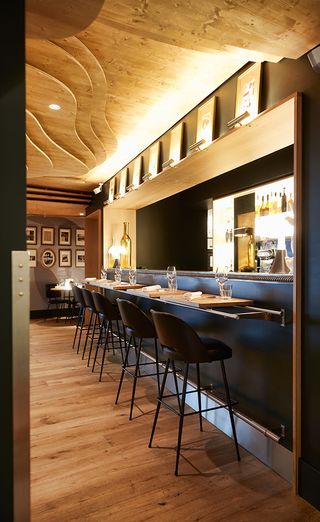A view along the bar with brown leather bar stools and individually lit family photographs above