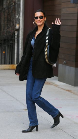 Bella Hadid wearing a black blazer with dark wash denim and a chain handbag
