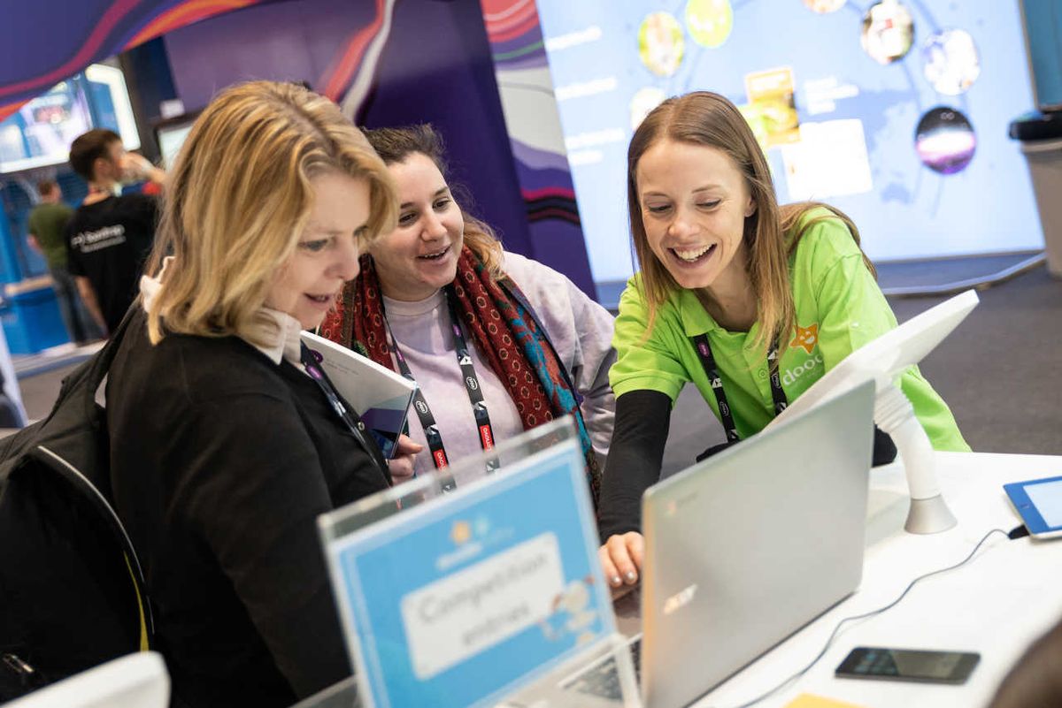 Smiling Bett attendees look at something interesting on a laptop computer