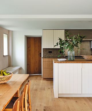 kitchen with wooden cream paneld cabinetry and wooden floors and wooden dining table and chairs