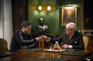 (L, R) Taron Egerton as Eggsy, raising a glass to Michael Caine as Chester King in Kingsman: The Secret Service