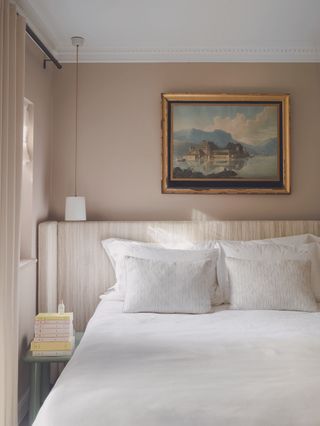 The bed with a striped textured headboard and painting hanging overhead