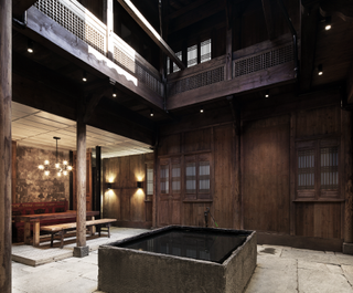 The Wuyuan Skywells Hotel in Shangrao. We see a courtyard with a square 'pool' filled with water and a tap at one end. The structure around the courtyard is made out of wood.