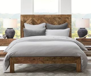 A wood bed frame in a traditional, bright bedroom